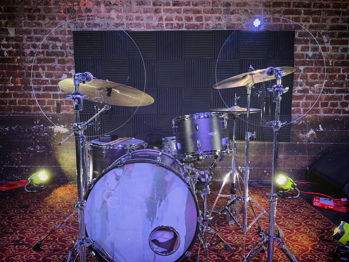 Two drum shield baffles on a drum set in front of Cymbal stands.